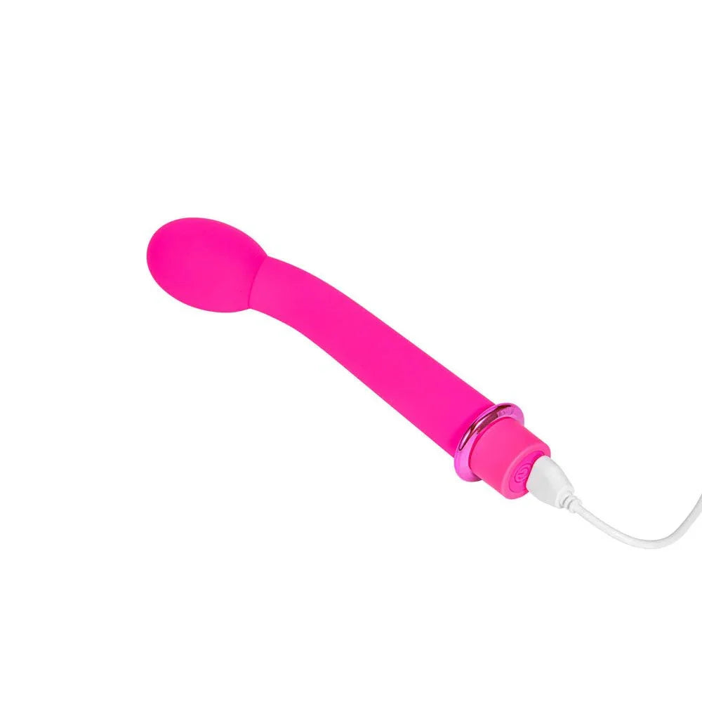 Maia Kora vibrator in Pink lying down with the charging cable plugged into the base