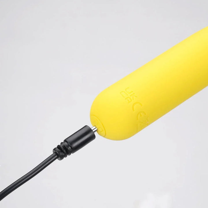 Maia Tawni bullet in Yellow on charge, black cable plugged into the base