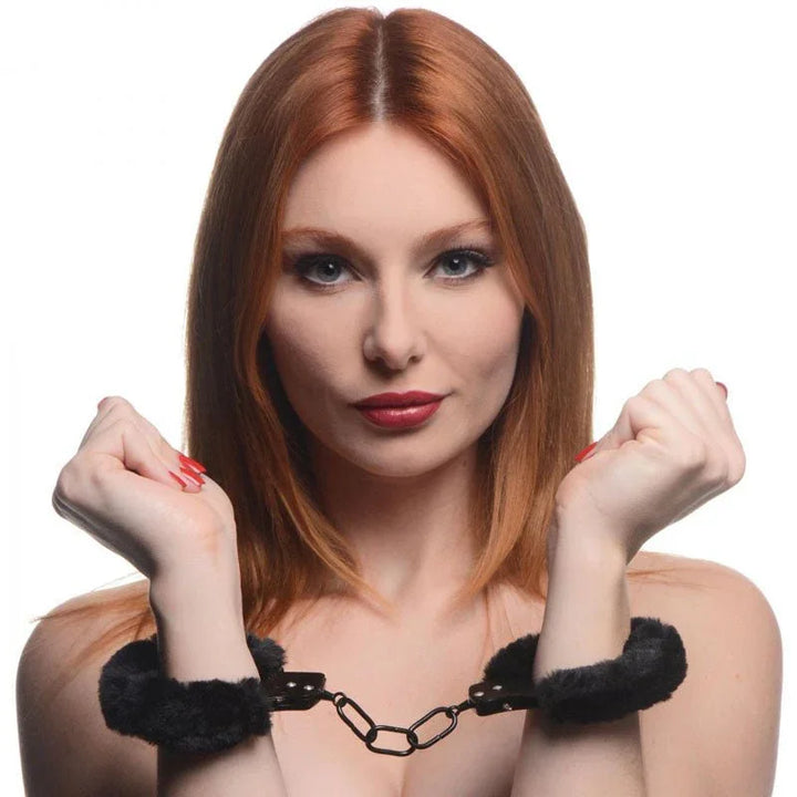 Cuffed in Fur black furry handcuffs worn on a woman's wrists, chain drawn between the cuffs