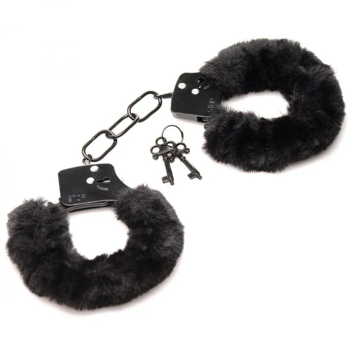 Black furry handcuffs laid open and flat on white with a two-key ring