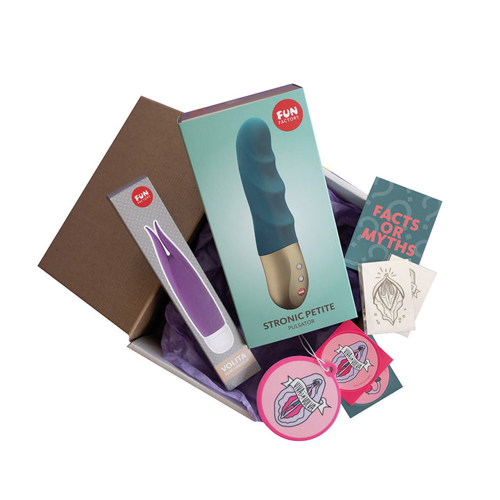 The image shows a collection of sex toys and accessories from Fun Factory, including a small blue and silver device, a small purple vibrator, and a pink circular toy, all displayed in an open box with branding and product information.