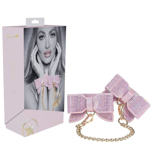 OUCH! Paris Handcuff Restraints in Pink, retail box beside the rhinestone bow cuffs and gold chain