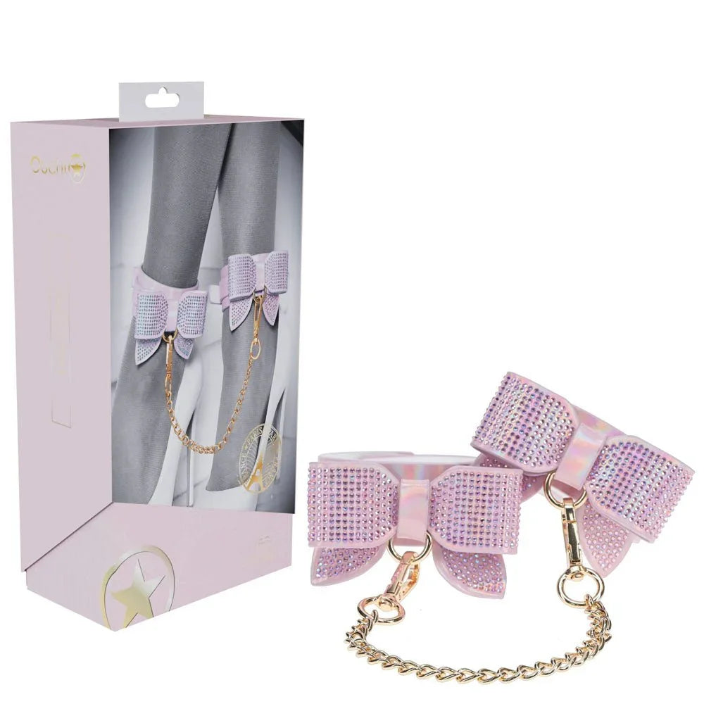 OUCH! Paris Leg Cuff Restraints in Pink, retail box beside the bow-trimmed leg cuffs and gold chain
