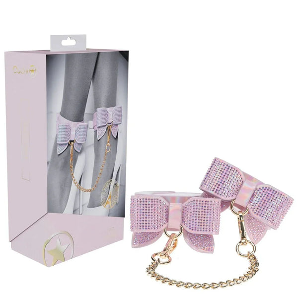 OUCH! Paris Leg Cuff Restraints in Pink, retail box beside the bow-trimmed leg cuffs and gold chain