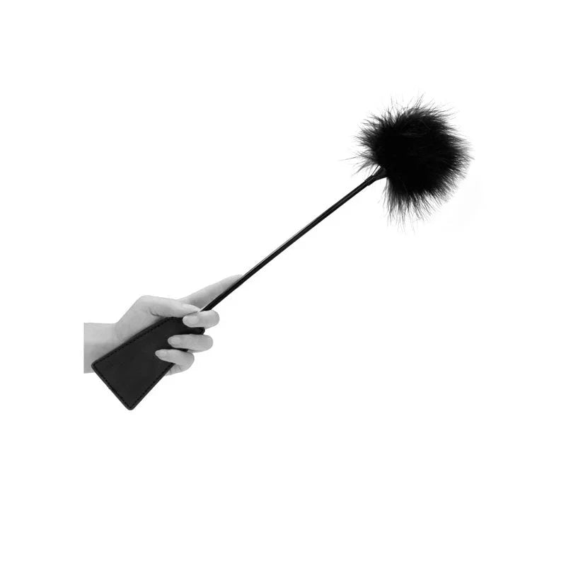OUCH! Black & White Crop with Feather Tickler in Black, held in one hand with the feather tip raised