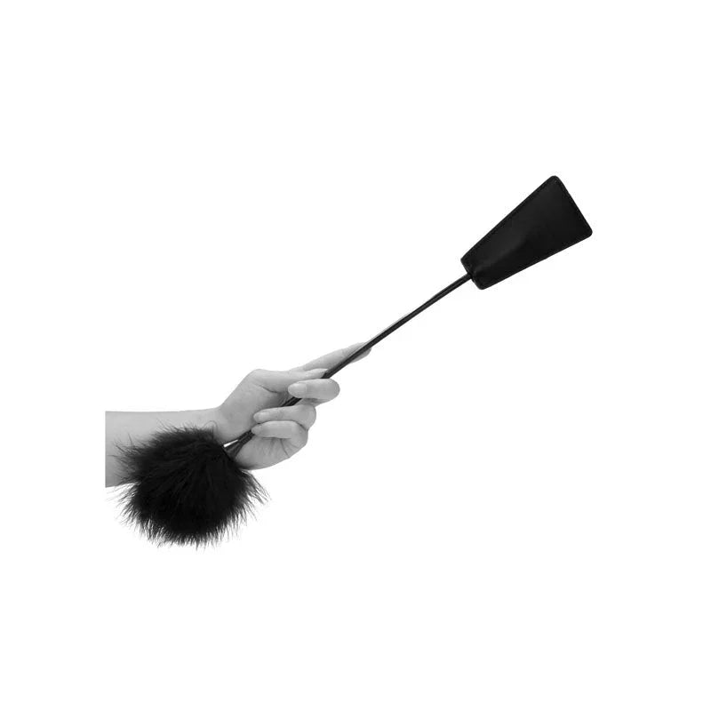 OUCH! Black & White Crop with Feather Tickler in Black, held in one hand with the leather slapper raised