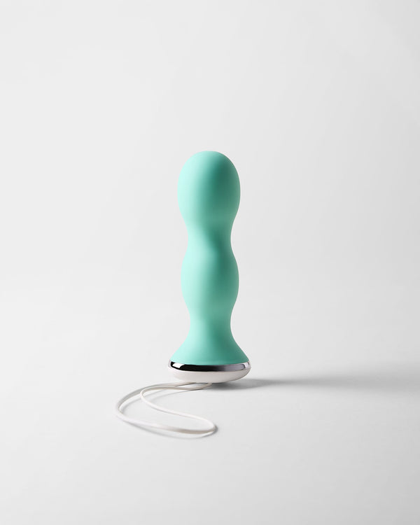 Perifit Care kegel trainer in green, standing upright on a light grey background with its white cord loop