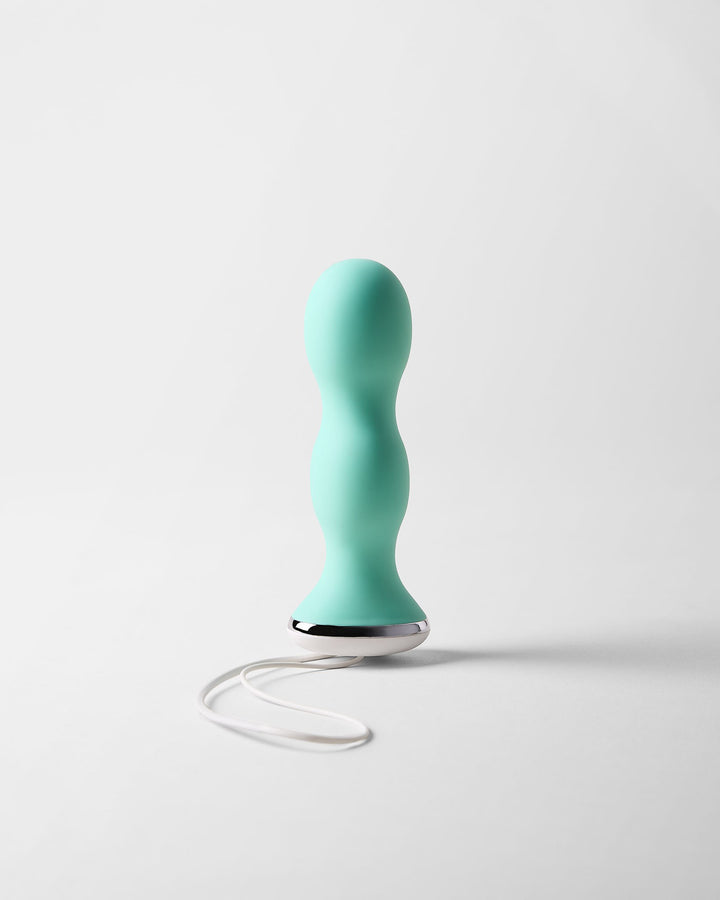 Perifit Care kegel trainer in green, standing upright on a light grey background with its white cord loop