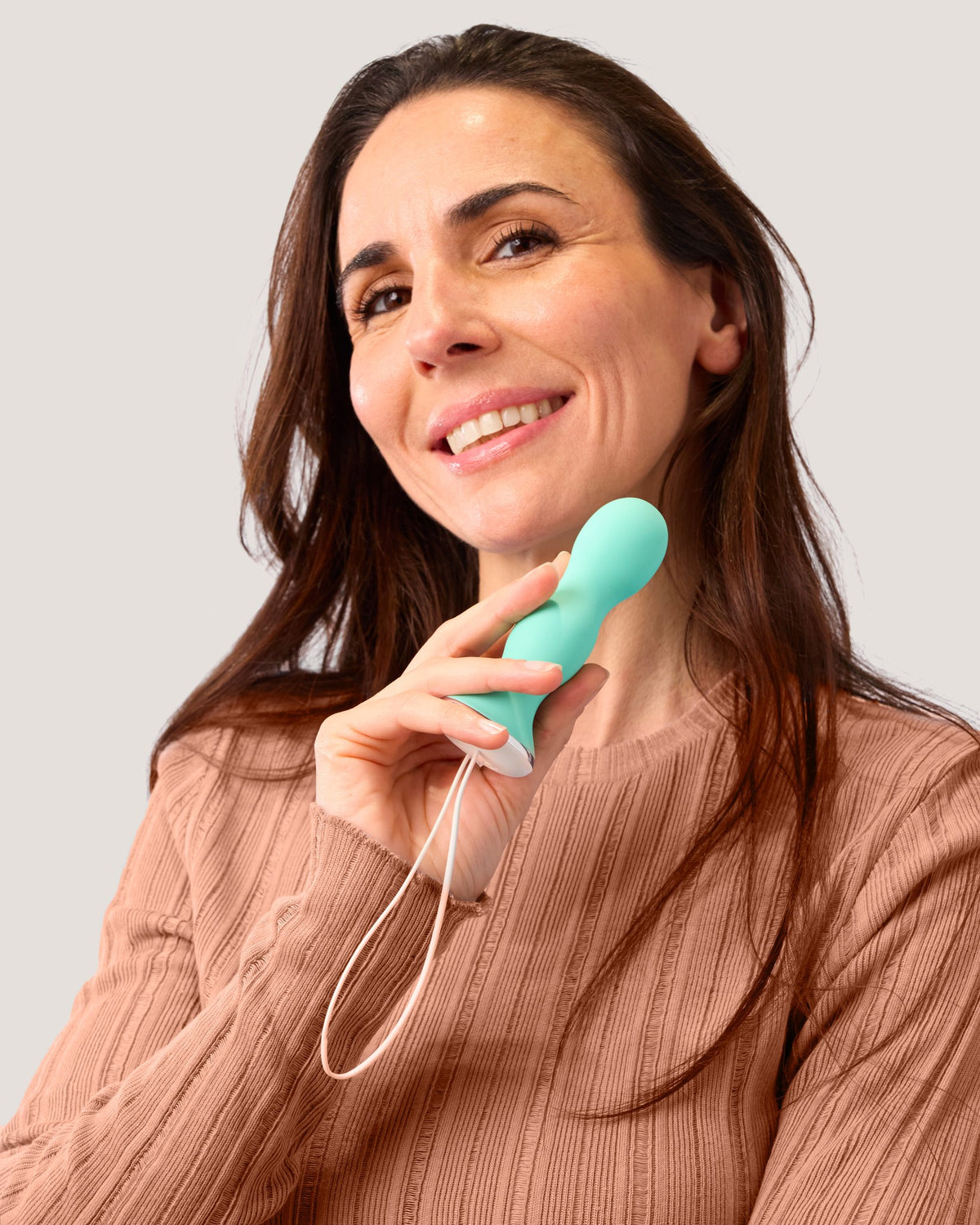 Smiling woman in a knit top holding a green Perifit Care by its cord