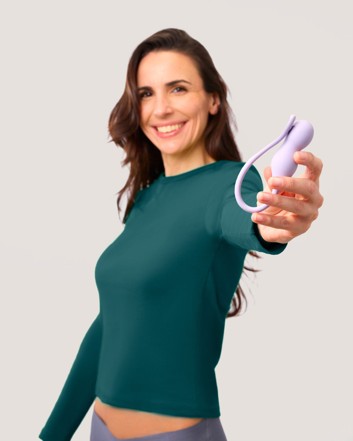 Smiling woman in a green top holding out a lilac Perifit Care+ trainer