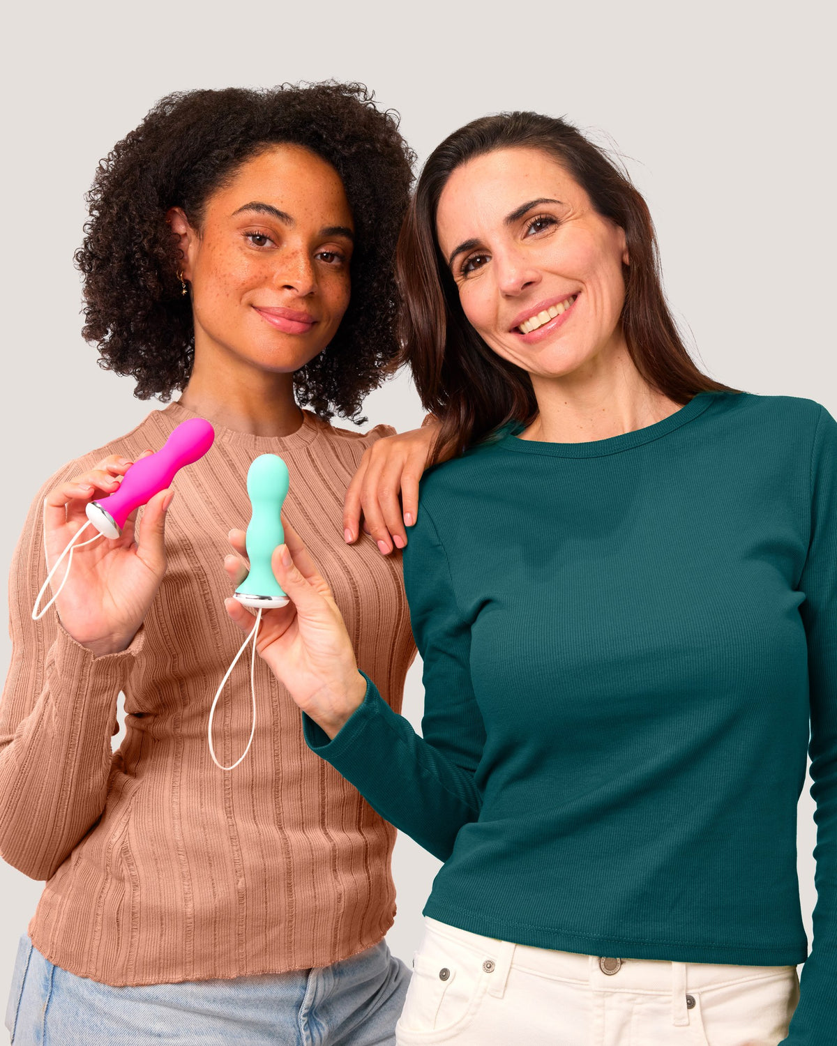 Two smiling women in casual tops holding a pink and a green Perifit Care