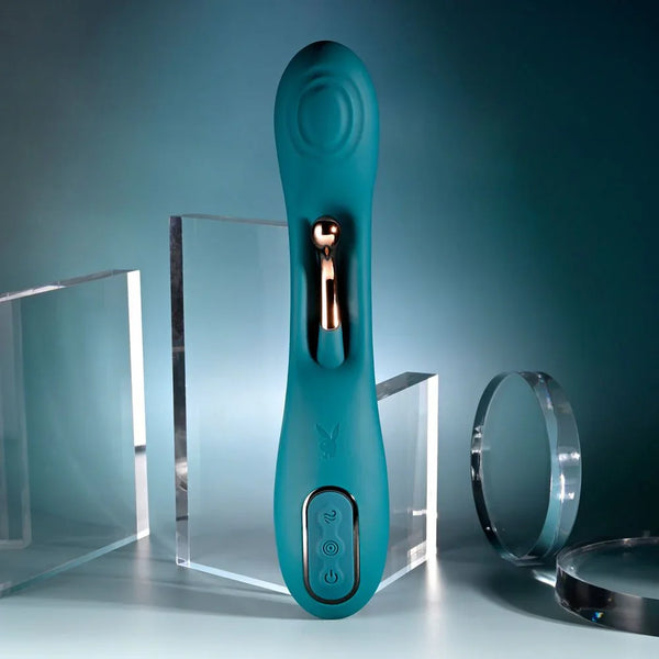 Playboy Pleasure Aurelie vibrator in green standing upright beside acrylic blocks