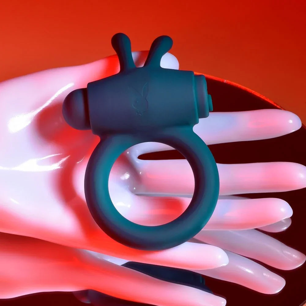 Bunny Buzzer cock ring resting on a white display hand under red lighting