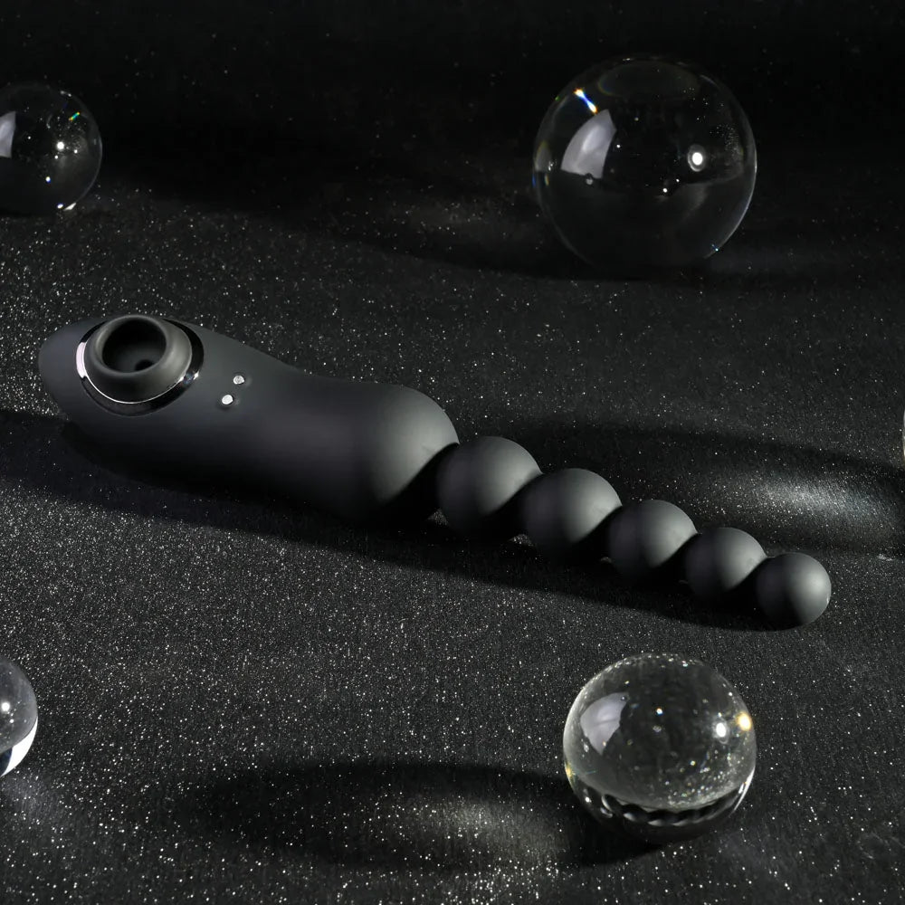 Black Let It Bead lying on a dark backdrop with glass spheres, suction end left