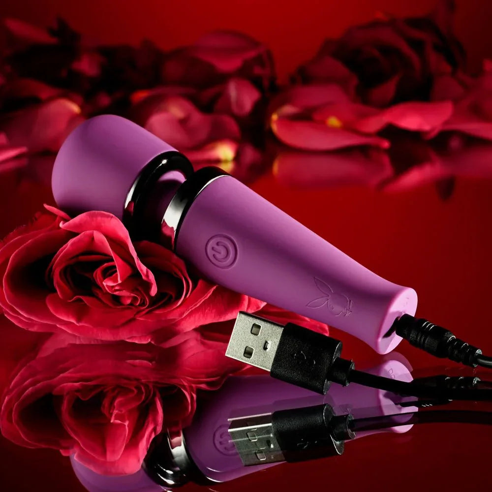 Purple Mic Drop wand with its USB charging cable connected, roses behind