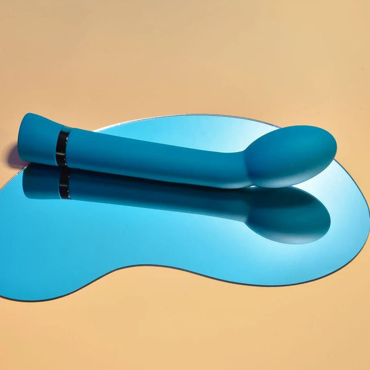 Blue On The Spot G-spot vibrator laid flat with the bulbous tip to the right