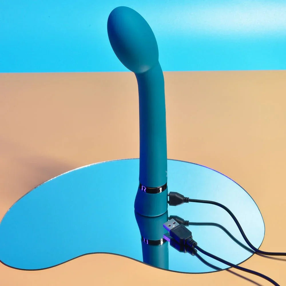 Blue On The Spot vibrator standing upright with its USB charging cable attached