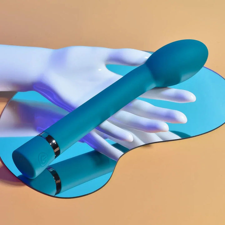 Blue On The Spot vibrator resting across a white display hand