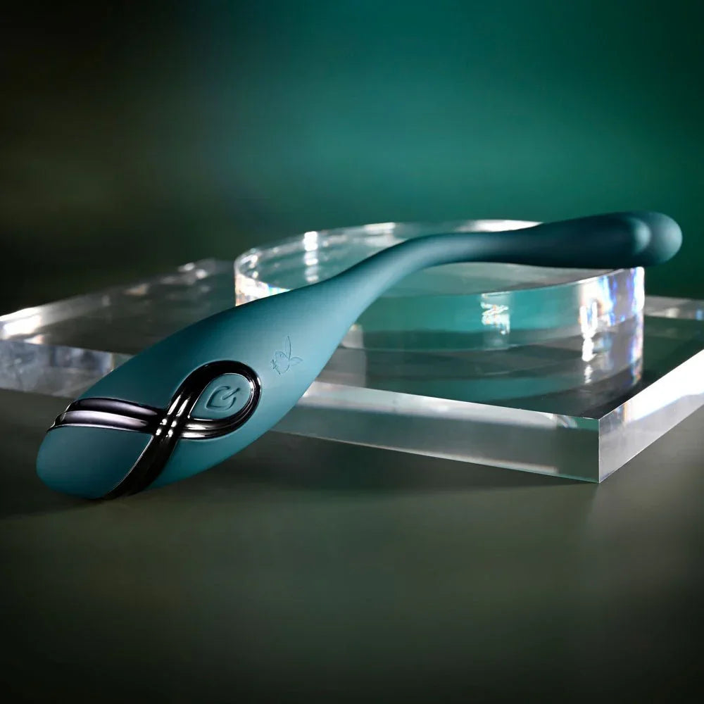 Green Pinpoint Perfection vibrator resting on a clear acrylic block, tail curved