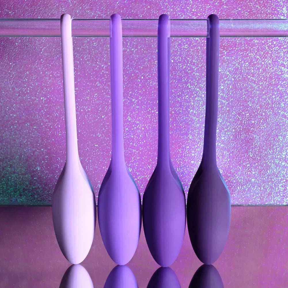 Four Put In Work kegel balls hanging by their cords in graduated shades of purple