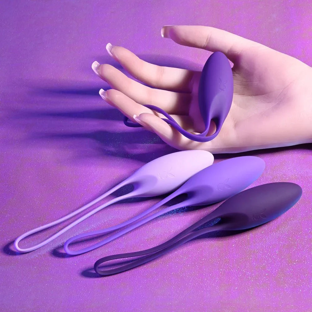 A single purple kegel ball held between finger and thumb, the rest of the set below