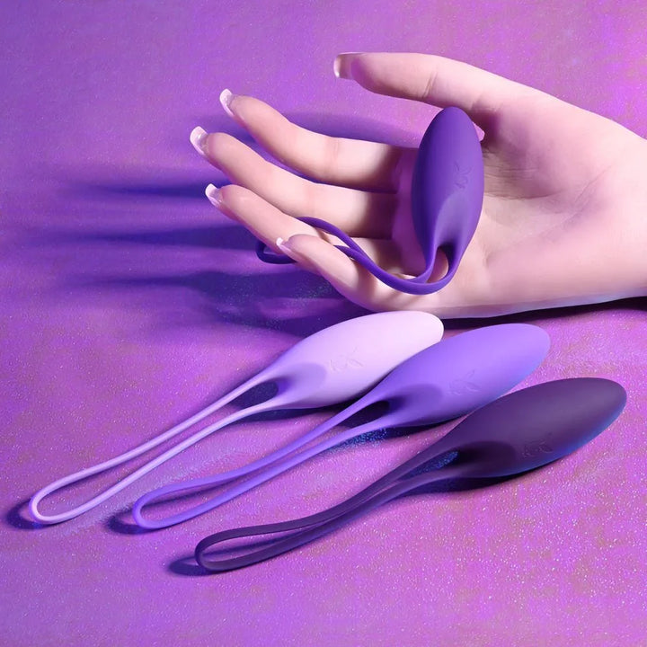 A single purple kegel ball held between finger and thumb, the rest of the set below