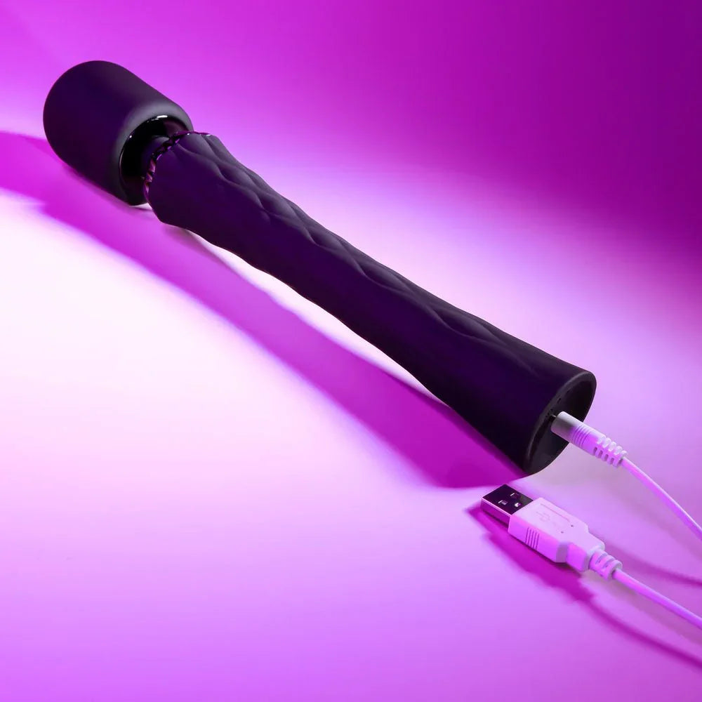 Black Royal massage wand lying down with its USB charging cable plugged in