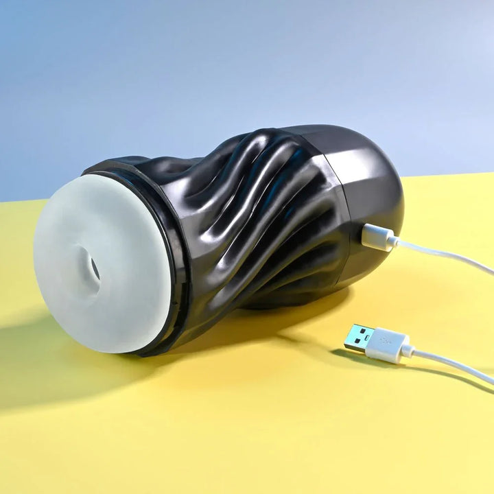 Black Solo stroker lying down with its USB charging cable connected