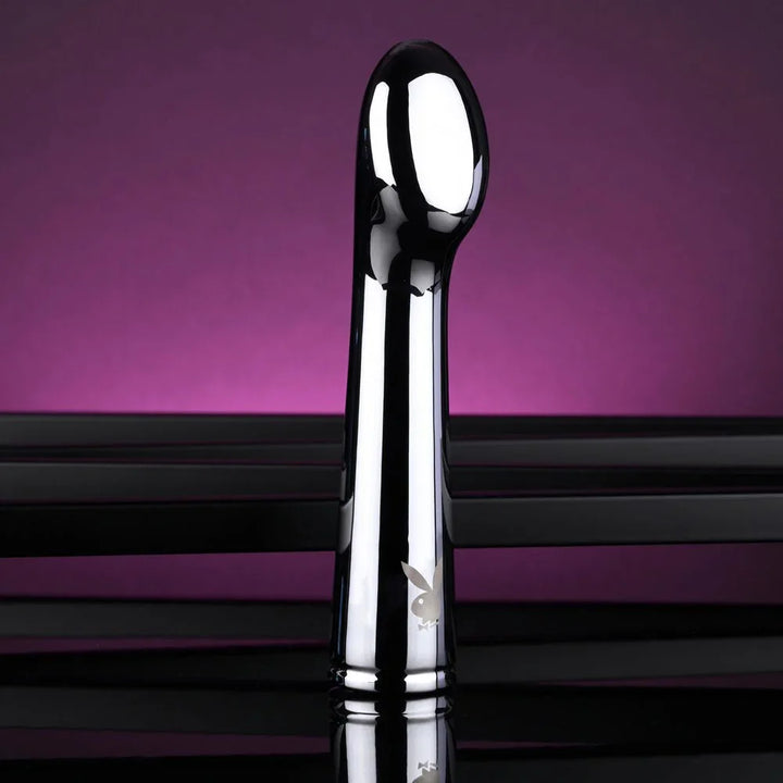 Chrome Swoon vibrator standing upright, front view under magenta lighting