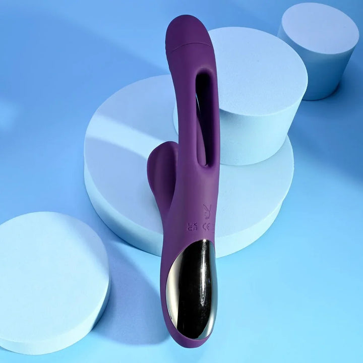 The Thrill in purple leaning on blue podiums, ribbed clitoral arm in view