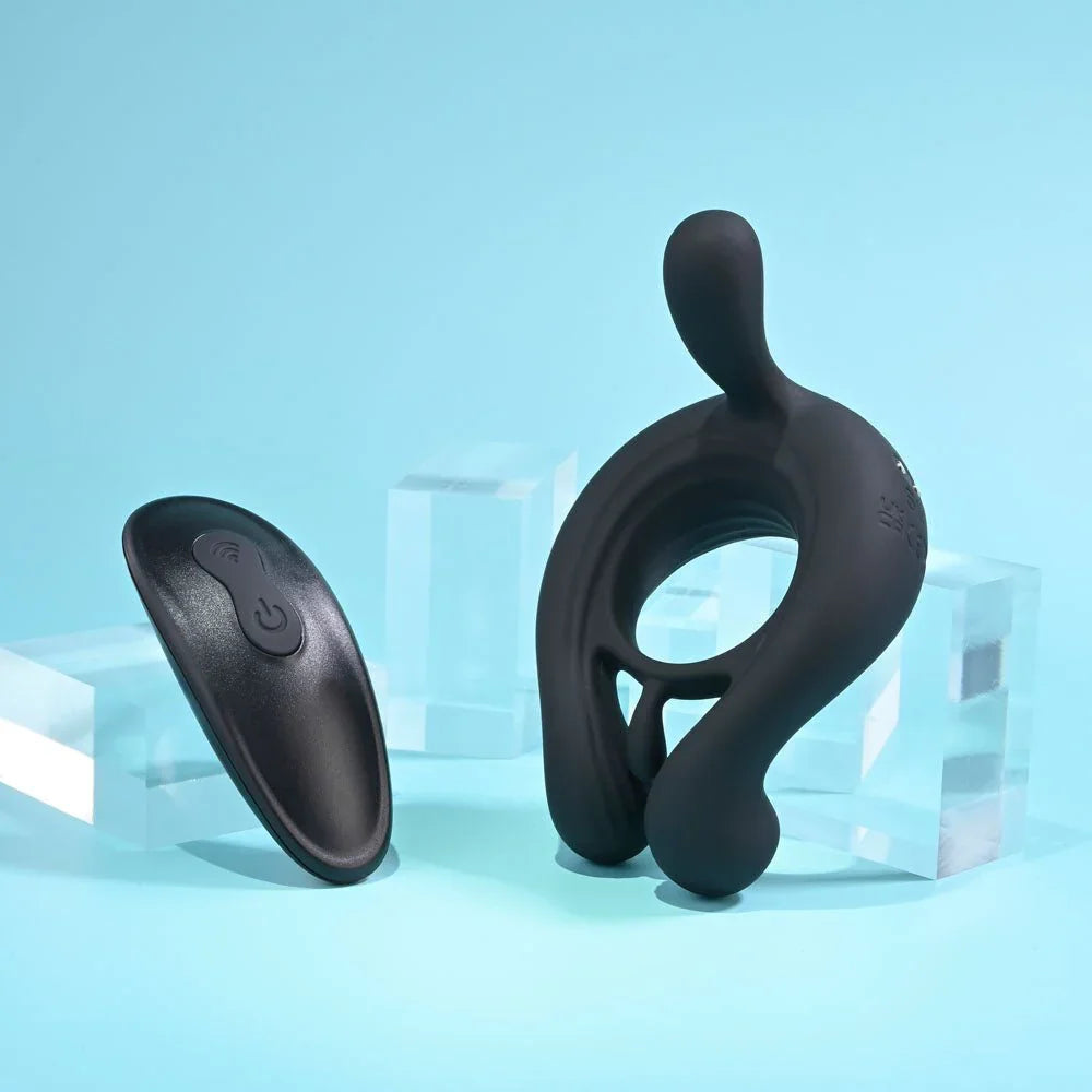 Black Triple Play cock ring standing upright with its oval wireless remote alongside