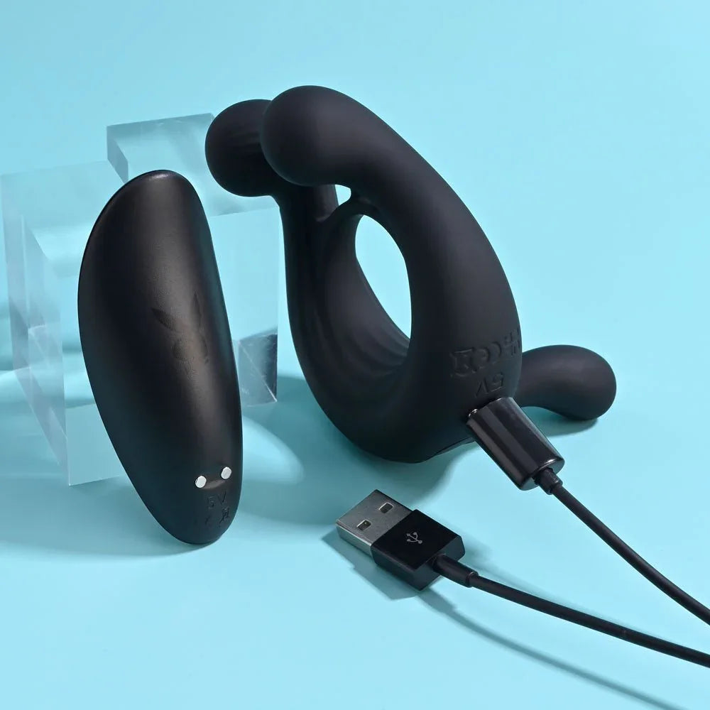 Triple Play cock ring lying beside its remote with the USB charging cable plugged in