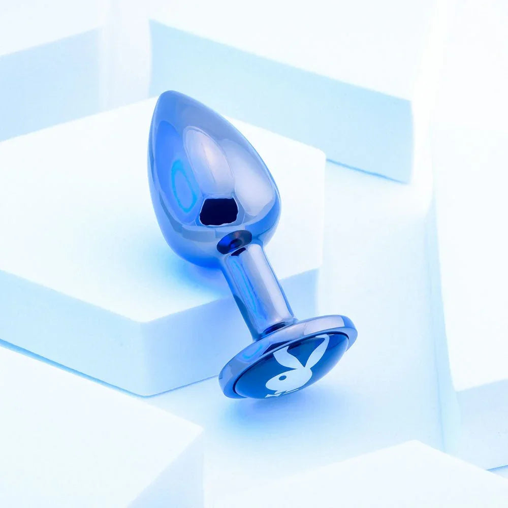 Chrome TUX butt plug resting on a white block with the base tilted to camera