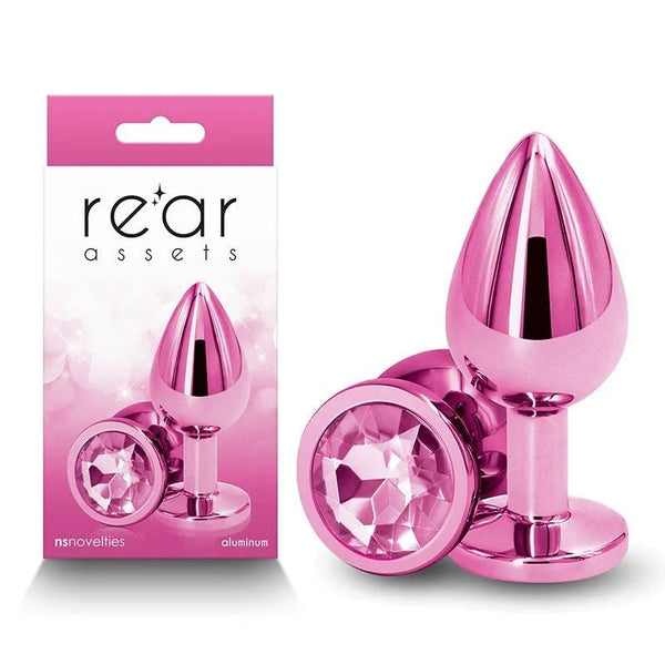 Rear Assets medium metal butt plug in Pink with a pink round gem base, beside its box