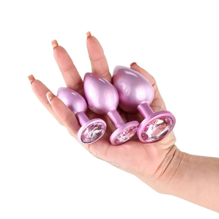 Rear Assets Trainer Kit in Iridescent Pink, all three plugs held in a hand for scale