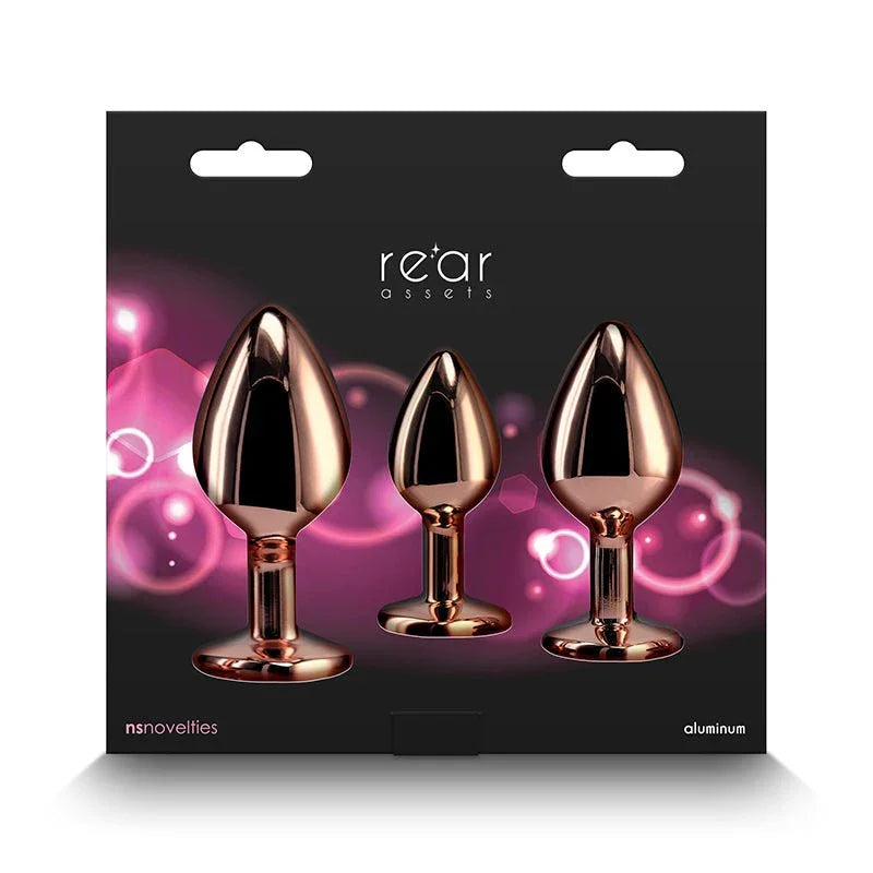 Rear Assets Trainer Kit retail box, three rose gold plugs on a pink glow background