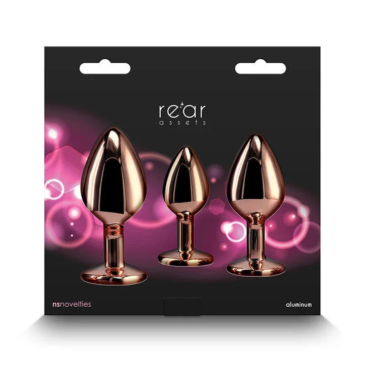 Rear Assets Trainer Kit retail box, three rose gold plugs on a pink glow background