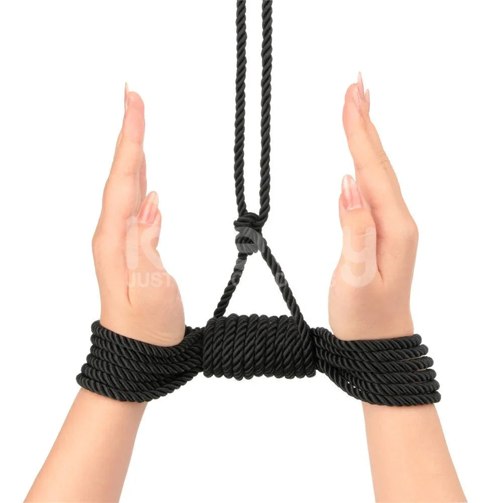 Two wrists bound and suspended with the black silky rope, hands raised