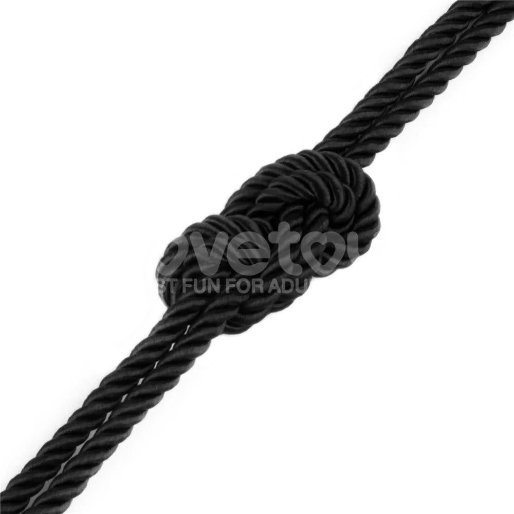 Single knot tied in the black silky rope, showing the twisted three-strand weave
