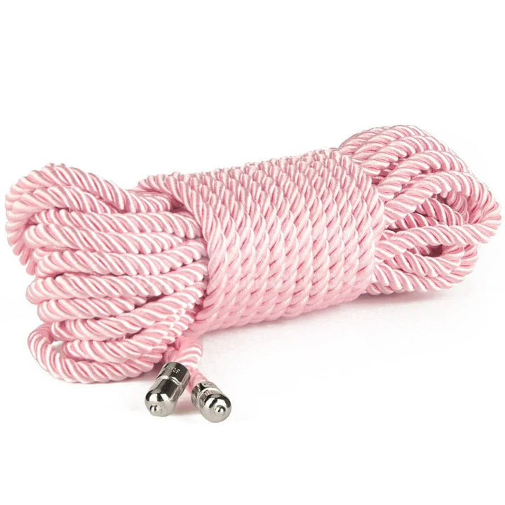 Bundle of pink silky bondage rope lying on white, metal-tipped ends to the front
