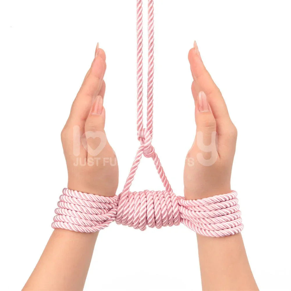 Two wrists tied with pink silky rope and lifted by an overhead line