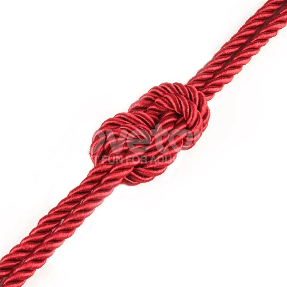 Single knot tied in the red silky rope, showing the glossy twisted strands