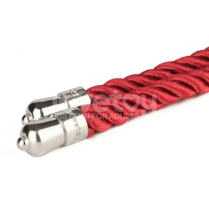 Close-up of the two polished metal tips finishing the red bondage rope