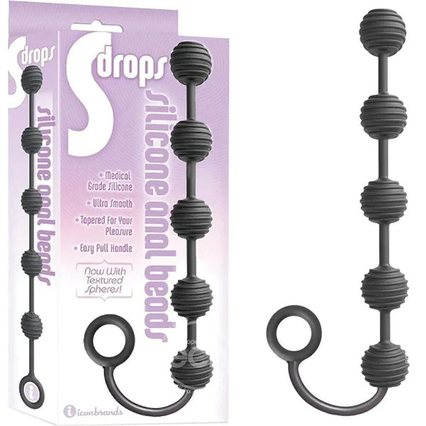 S-Drops silicone anal beads in Black, four ribbed spheres on a pull ring, beside the box