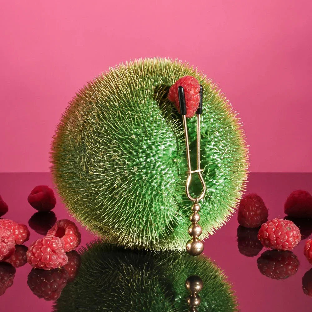 A beaded clamp gripping a raspberry on a spiky green fruit