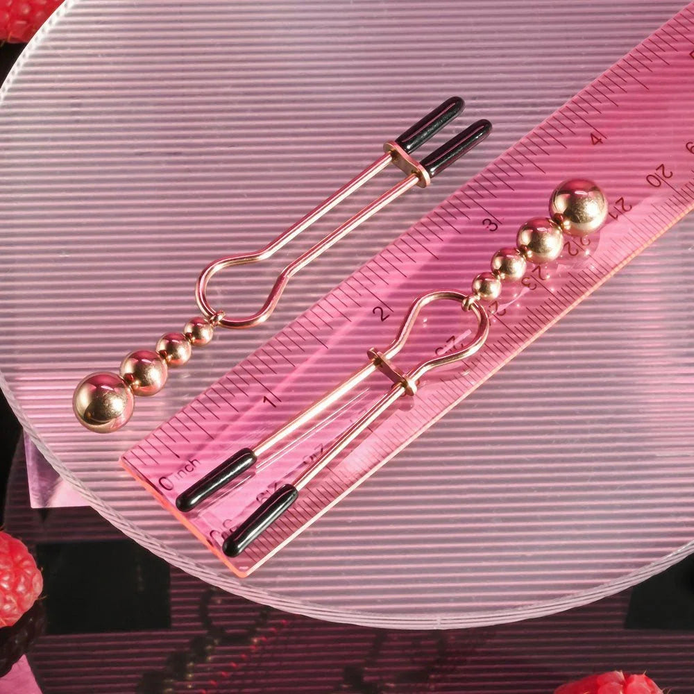 Rose gold beaded nipple clamps on a ribbed disc, measured against a small ruler