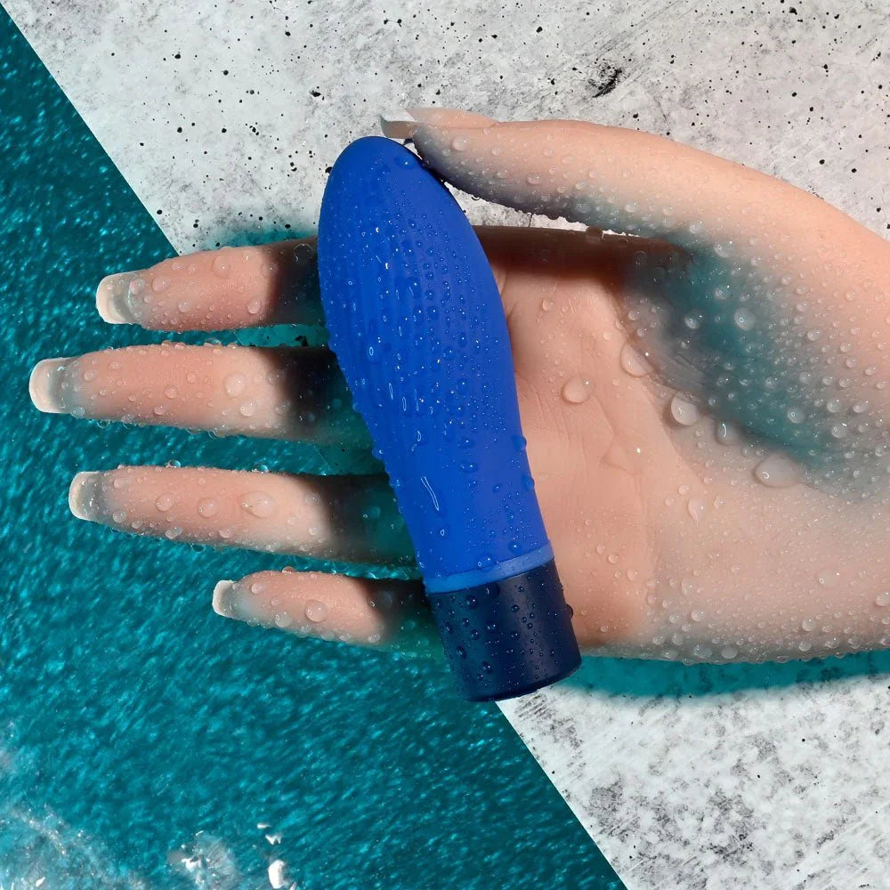 Cobalt Cutie held on a wet hand at the edge of the water