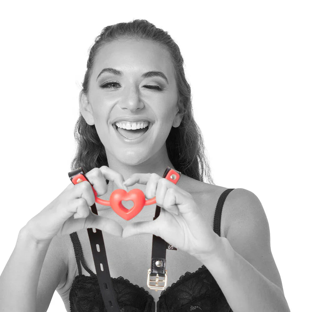 Model forming a heart with her hands around the red heart gag