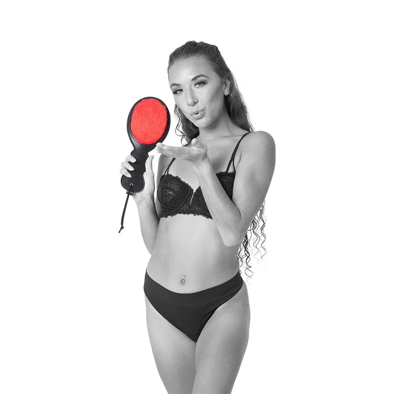 Model holding the red Amor Paddle up beside her face