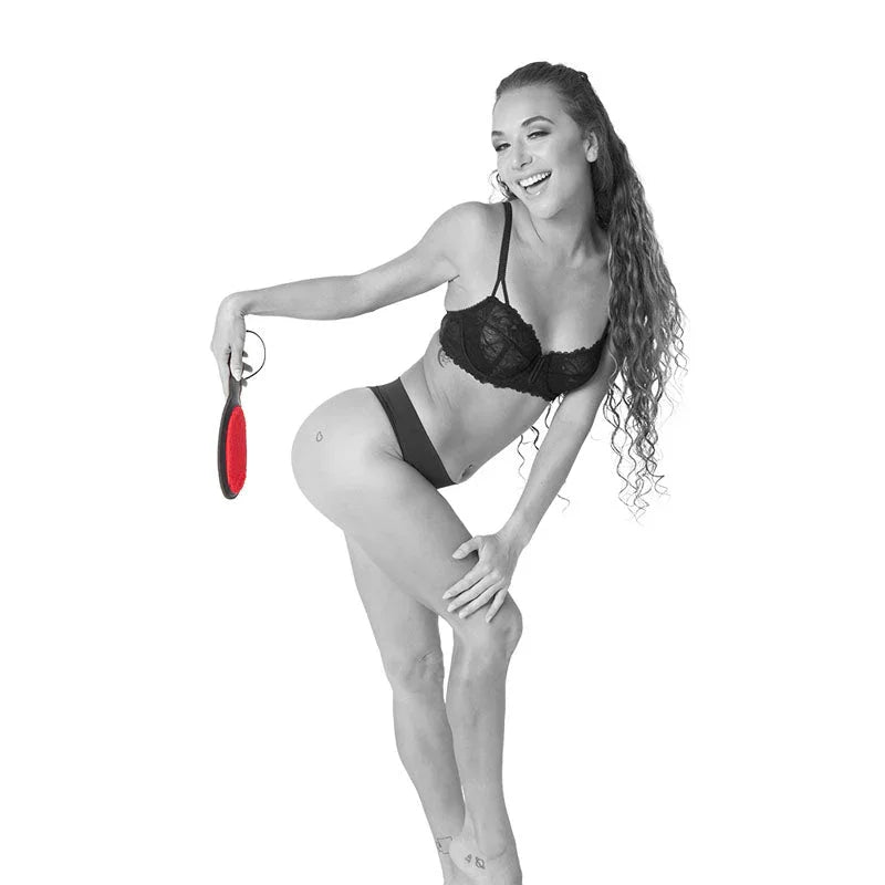 Model bending forward holding the Amor Paddle beside her thigh